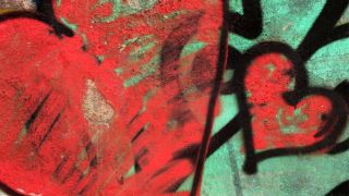 Das Bild zeigt eine Wand mit grünem Hintergrund und roten Herzen, die schwarz umrandet sind.