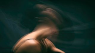 Man sieht den Kopf und Rücken einer Frau im verschwommenen Licht.