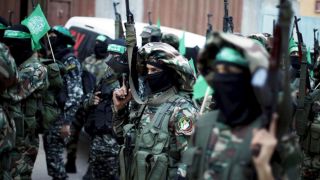 Das Bild zeigt zahlreiche Soldaten mit Waffen in der Hand und grünen Flaggen und arabischer Aufschrift.