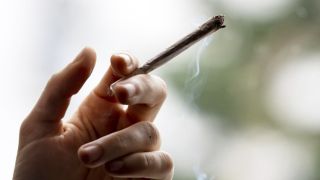 Hand mit Joint der raucht