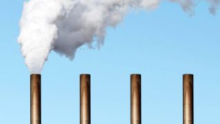 Man sieht vier Schornsteine und aus dem ganz rechts steigt weißer Rauch auf.