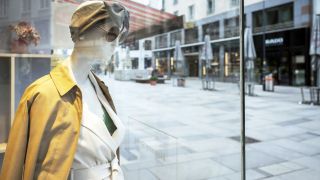 Man sieht die Kärtnerstraße in Wien im Hintergrund mit Geschäften ohne Menschen auf der Straße. Links im Vordergrund sieht man eine Schaufensterpuppe.